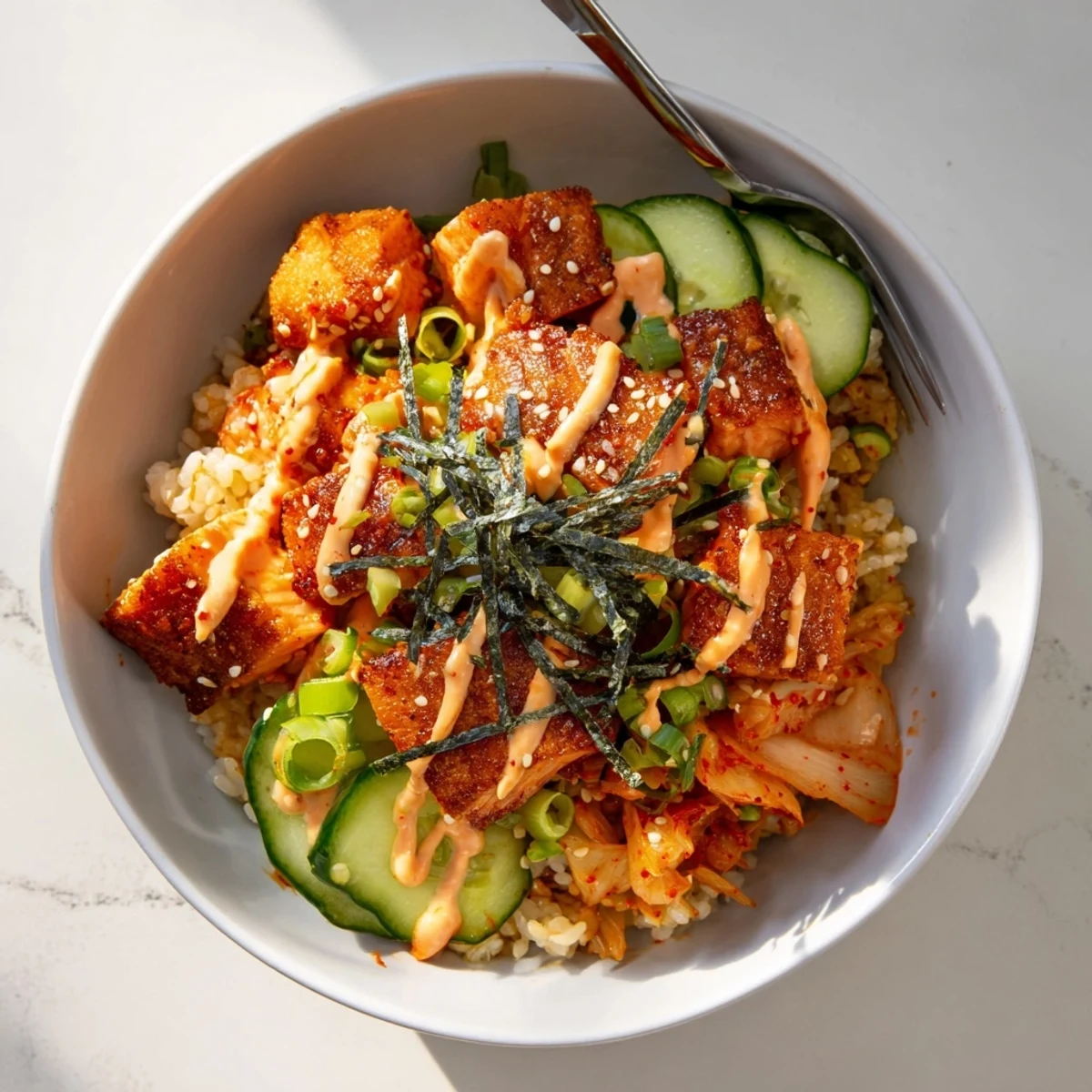 Crispy Salmon Rice Bowl garnished with avocado, kimchi, and spicy mayo drizzle.  