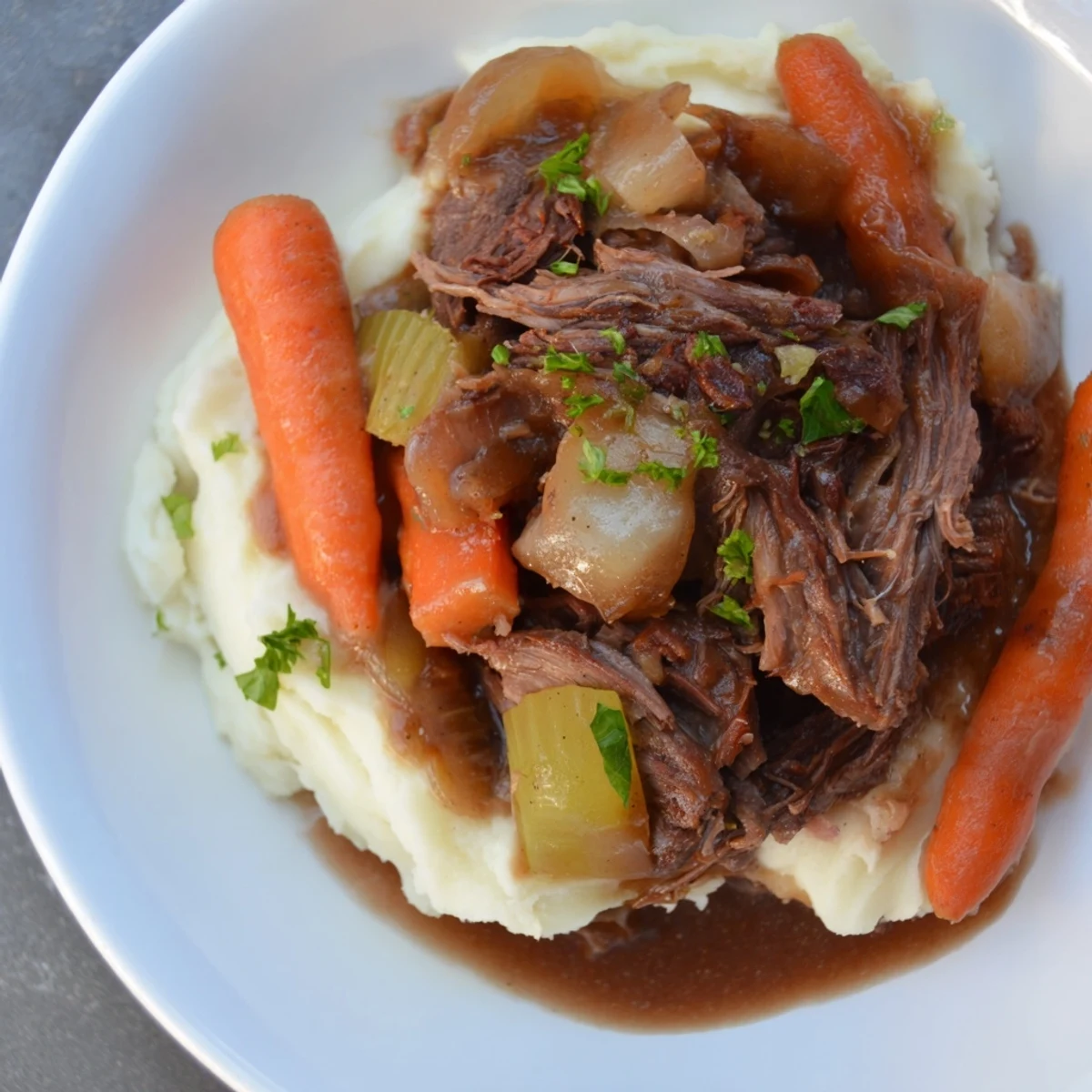 Tender slow cooker pot roast with vegetables and creamy mashed potatoes, ready to serve.