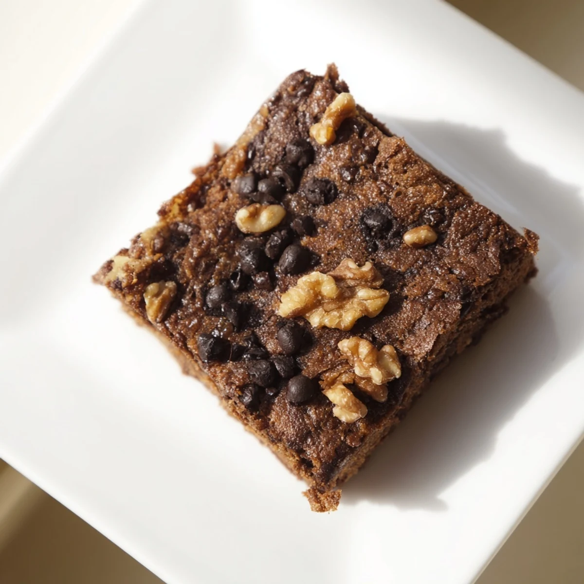 A tray of baked sweet potato brownies, featuring visible chocolate chips and a slightly cracked surface.