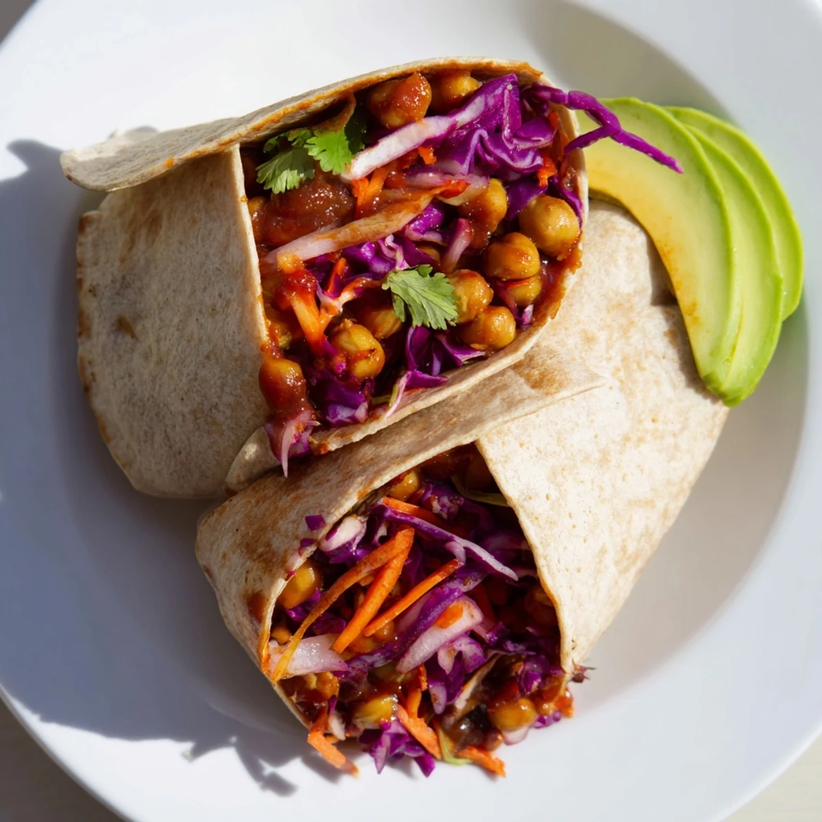 This BBQ Chickpea & Slaw Wrap shows a fully wrapped tortilla, cut in half, revealing its fresh ingredients.