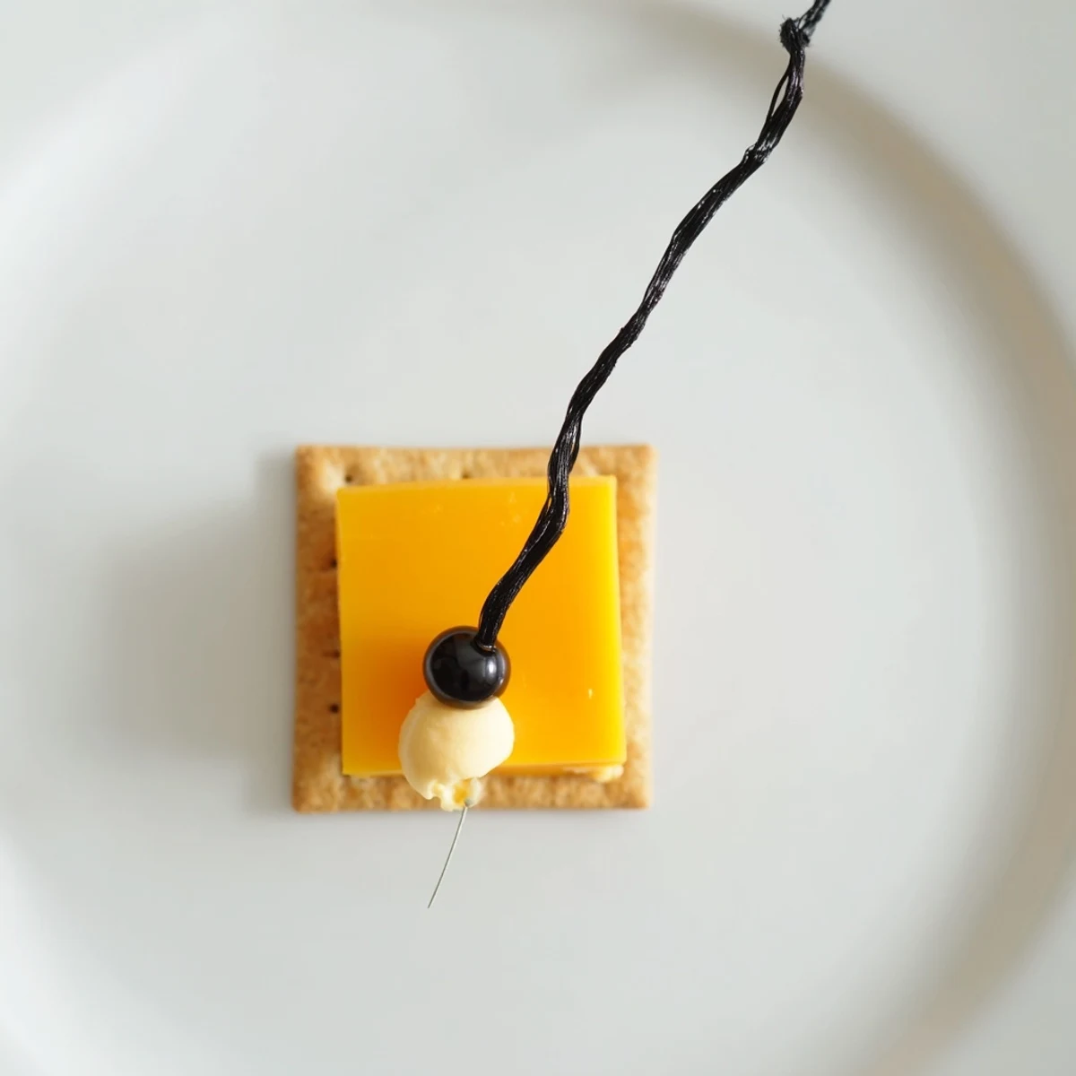 Close-up of a delightful Graduation Cap Snack; cheese squares, crackers, and licorice, ready to eat.