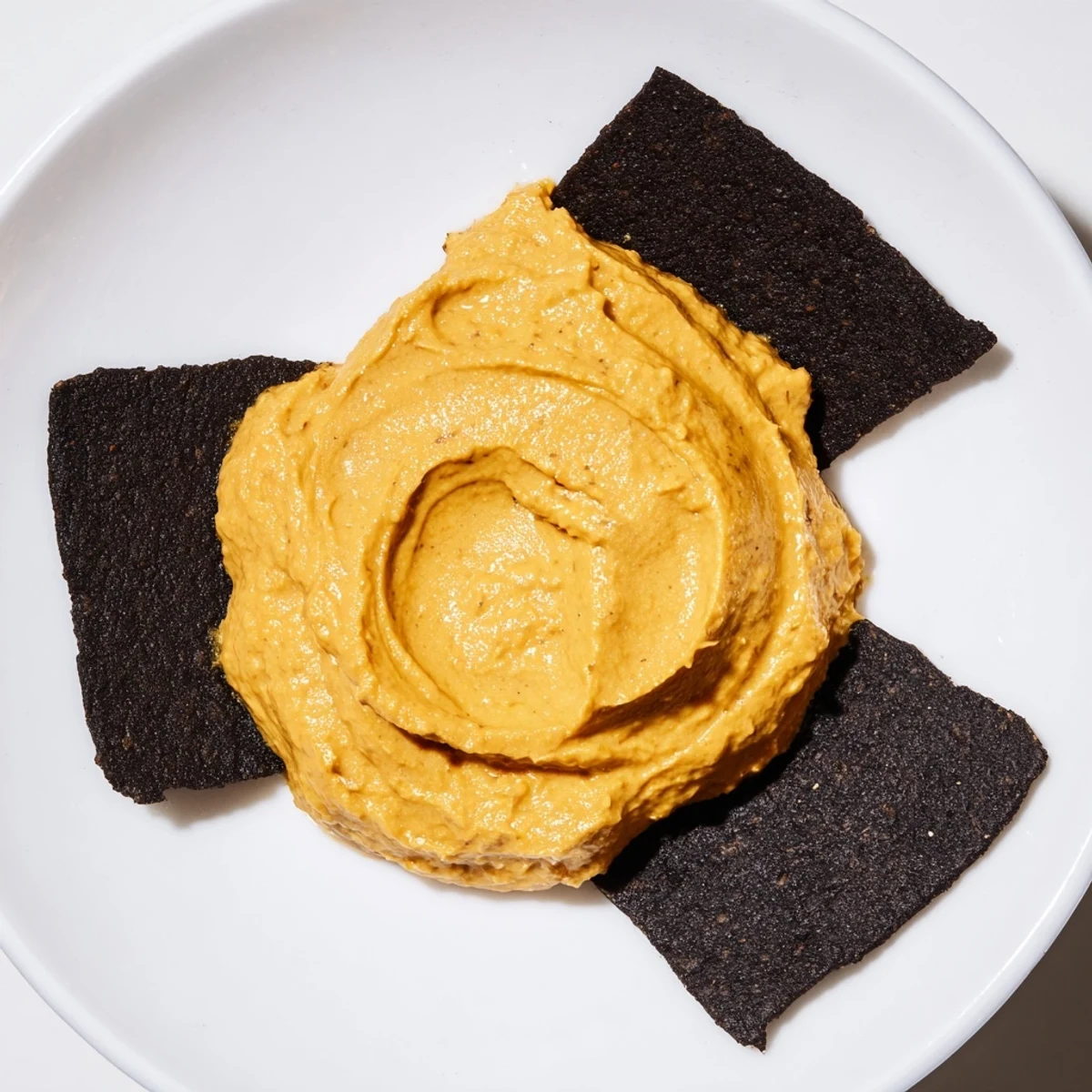 Imagine The Midnight Sun: a creamy, golden carrot dip encircled by crispy black charcoal crackers.