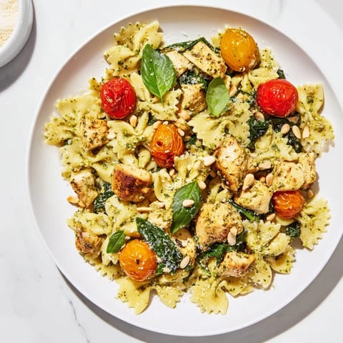 A close-up of pesto chicken bowtie pasta, showcasing tender chicken and fresh basil pesto sauce.