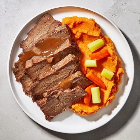 A close-up shows juicy, slow-cooked Classic Brisket & Mashed Sweet Potatoes, ready to be enjoyed.