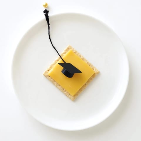 Festive Graduation Cap Snacks: savory cheese squares topped with licorice tassels, perfect for party appetizers.