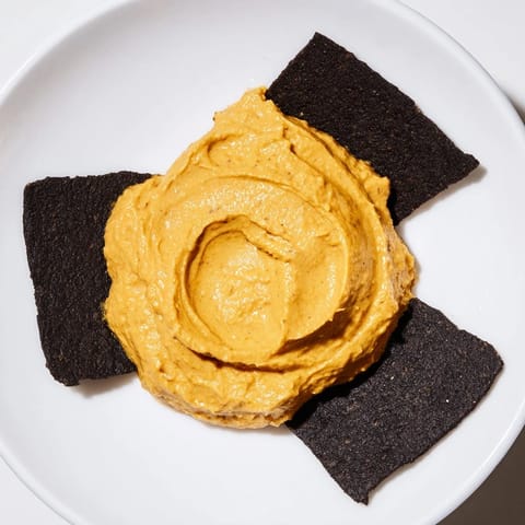 Imagine The Midnight Sun: a creamy, golden carrot dip encircled by crispy black charcoal crackers.