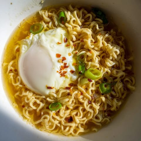 Enjoy flavorful Upgrade Instant Ramen with Egg, served hot and garnished with fresh scallions and chili flakes.