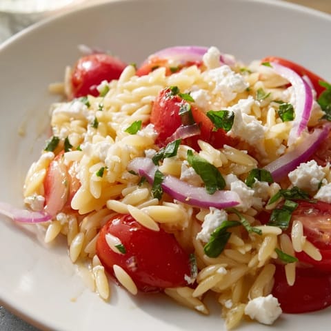 A close-up of a flavorful Tomato Feta Orzo dish with herbs, ideal for a light Mediterranean meal.