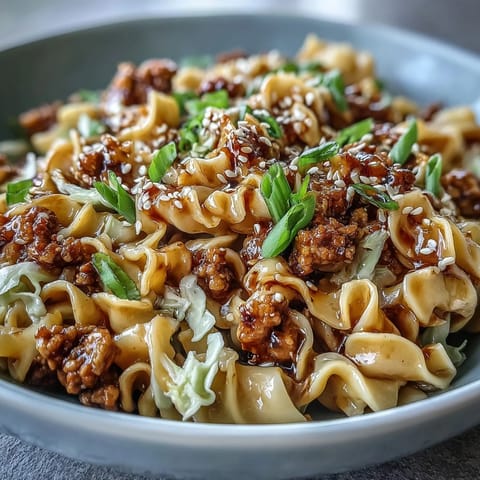 Savory Creamy Potsticker Noodle Stir-Fry served steaming hot in a skillet, topped with sesame seeds and chili crisp. 