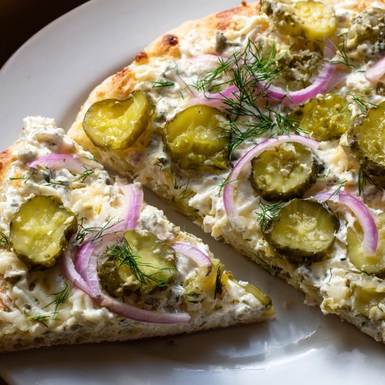 A unique pickle pizza garnished with fresh dill, hot from the oven.