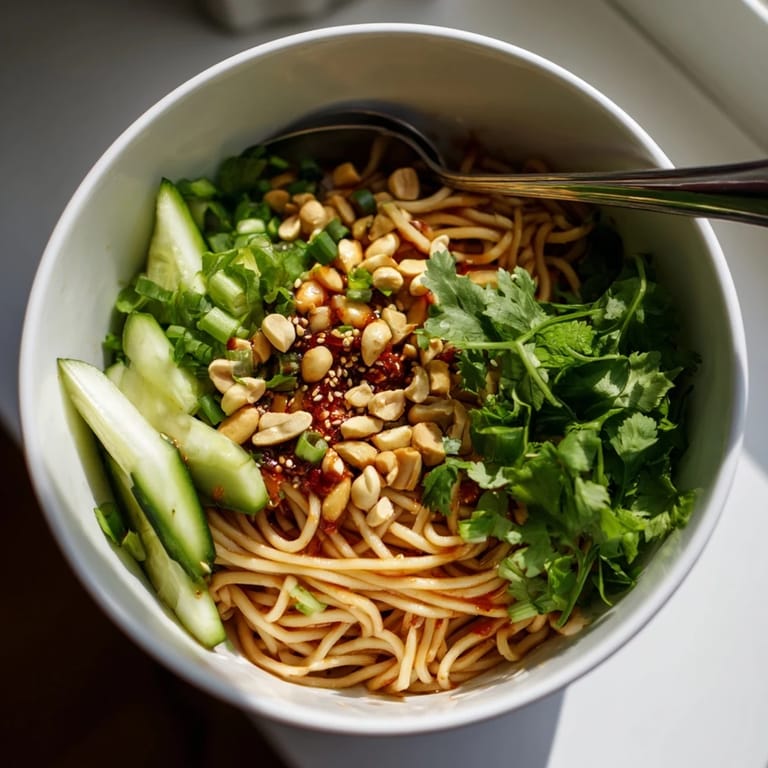 Serving suggestion for a spicy sesame noodle salad with vibrant vegetables and herbs, perfect for a quick vegetarian lunch or light dinner.
