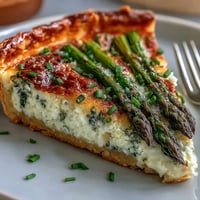 Elegant asparagus ricotta tart with crisp puff pastry, creamy cheese filling, and fresh lemon zest garnish.